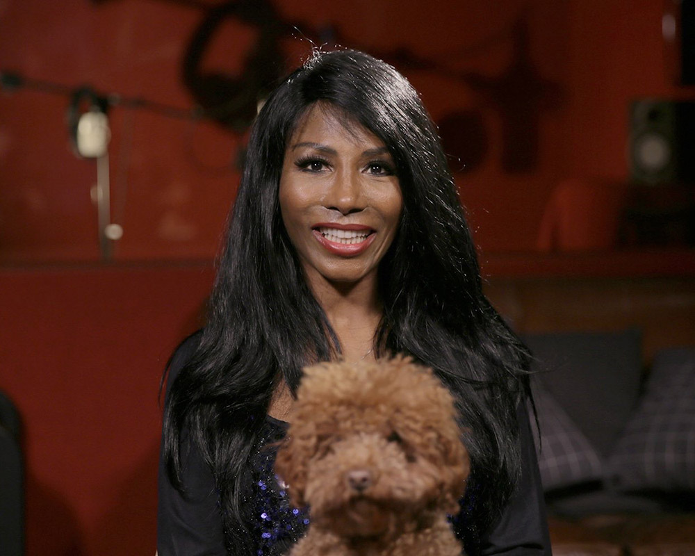 sinitta smiling with dog on her lap