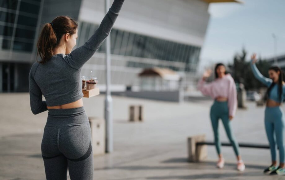 Woman-in-fitness-attire-greeting-friends-in-urban-setting-showcasing-active-lifestyle-and-friendship-2048x1365