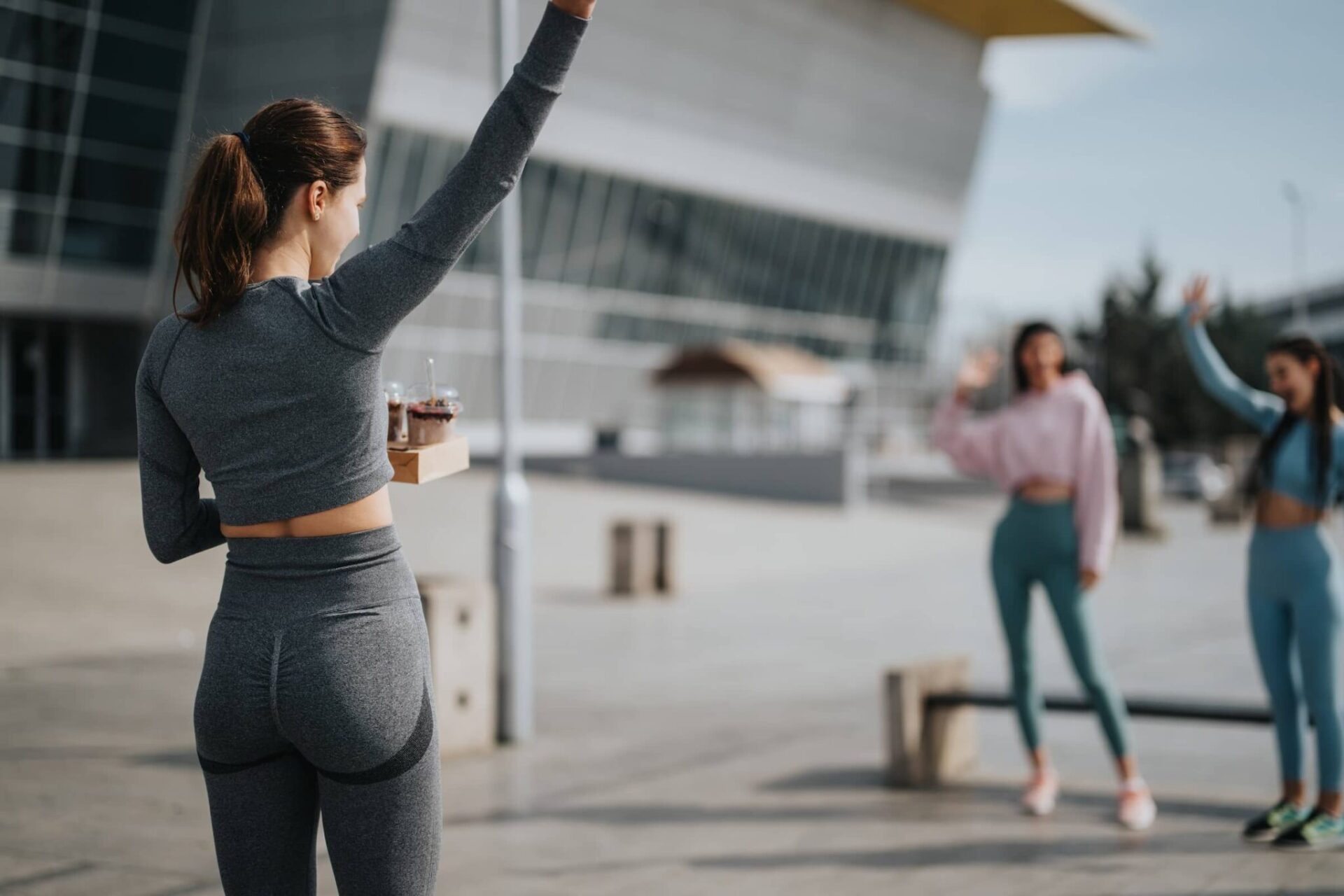 Woman-in-fitness-attire-greeting-friends-in-urban-setting-showcasing-active-lifestyle-and-friendship-2048x1365